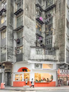 two people walk past an apartment building with balconies on the windows and balconyes