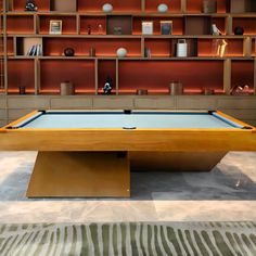 a pool table in the middle of a room with shelving on the wall behind it