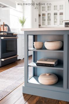 a kitchen with blue cabinets and white walls, wood flooring and an oven in the background