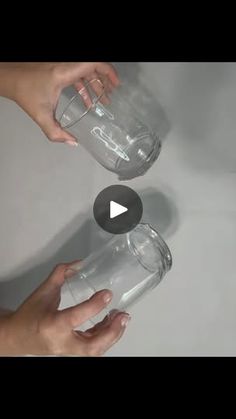 two hands are pouring water into a clear glass cup with the lid down and another hand is reaching for it