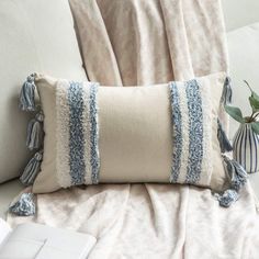 a white couch with two pillows on it and a vase filled with flowers next to it