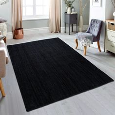 a large black rug in a living room next to a chair and window with curtains