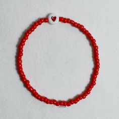 "At Marche Des Perles we make all our seed bead bracelets to order. The \"red heart bracelet\", inspired by our love of the breton stripe. A red heart, surrounded by red coloured beads on an elastic chain, tied neatly together at the end. We recommend not to pull too hard on the elastic or this could permanently stretch the bracelet, or worse, break it. we'd also suggest taking it off before showering to avoid discolouration or damage." Cheap Red Heart-shaped Beaded Bracelets, Small Beaded Bracelets Red, Red Heart Bracelet, Parts Of The Heart, Red Beaded Bracelet, Bracelet Inspired, Bead Bracelets, Seed Bead Bracelets, Red Bead