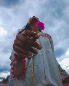 a woman holding a pink flower in her hand