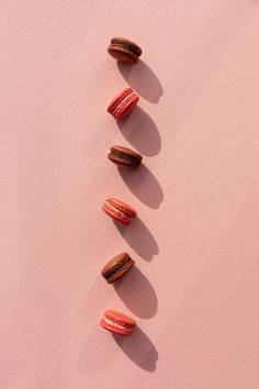 three donuts are lined up in the shape of a line on a pink surface