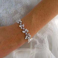 a woman's arm wearing a wedding bracelet with crystal stones and pearls on it