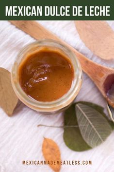 a jar of homemade mexican dulce de leche on a table with leaves and spoons