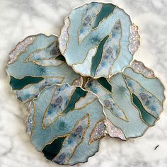 three blue and green plates sitting on top of a white tablecloth covered floor next to each other