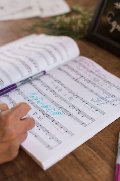 someone is doing music notes on a book with a pen in their left hand and another notepad next to them