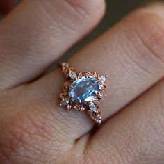 a woman's hand with a ring on it that has an oval blue stone in the center