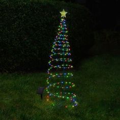 a lighted christmas tree sitting in the grass