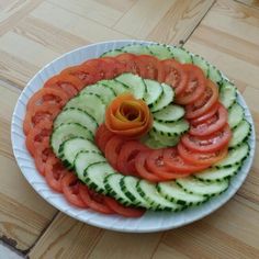 a white plate topped with sliced cucumbers and tomatoes