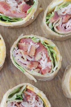 several sandwiches with bacon and lettuce on them sitting on a wooden table top