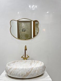 a bathroom with a marble sink and gold faucet on the wall above it