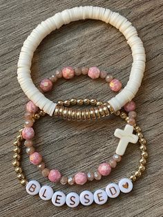 This elegant and feminine bracelet stack is designed with a set of three handmade beaded stretch bracelets.  Blessed is spelled out with rose gold colored letter discs beads and encompassed with tiny gold toned spacer ball beads.  White Heishi clay polymer flat discs are detailed with gold colored flat spacer rounds.  A stone cross is encircled with Czech glass beads in pink tones.  Wear each bracelet separately or stack them together!   **Personalize with any name or word. Please keep in mind t Winter Paper, Jewelry Stacking, Clay Bead Necklace, Preppy Bracelets, Layering Jewelry, Homemade Bracelets, Cross Gold, Stone Cross, Christian Bracelets