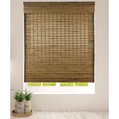 a bamboo blind in a room with white walls and wood flooring, along with a potted plant on the window sill