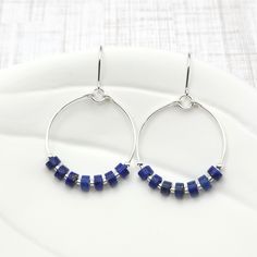 Add a touch of bohemian charm to your look with our Boho silver hoops featuring stunning lapis lazuli gemstones. Handcrafted with care, these sterling silver earrings are the perfect accessory for any free-spirited soul. Embrace your inner boho with these unique and stylish hoops! .925 Sterling Silver Measure approximately 1.125" in diameter Earrings Hang 1.75" from top of ear wire Lapis Lazui Gemstones Polished to a high shine Sent in a Gift Box with Polishing Cloth Handmade in Montana African Turquoise, Free Spirited, Jewelry Packaging, Silver Hoops, Ear Wire, Lapis Lazuli, Sterling Silver Earrings, Montana, Silver Earrings