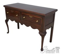 a wooden desk with two drawers and gold pulls on the bottom drawer, against a white background