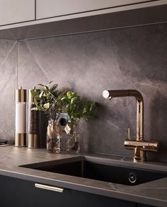 a kitchen sink with gold faucet and marble counter top in front of it