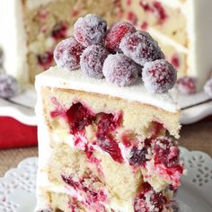 a cake with white frosting and berries on top is cut in half to show the inside