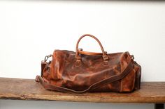 Introducing our stunning Vintage Leather Duffel Bag, the perfect accessory for those who appreciate style and functionality. Crafted from premium-quality materials, this bag is made of genuine leather and has a unique and eye-catching finish. The spacious main compartment of the duffel bag is perfect for packing clothes, shoes, and other essentials for a weekend getaway or gym session. The interior is lined with soft fabric to protect your belongings, and there are two open pockets and a zippere Vintage Luxury Duffle Bag With Large Capacity, Luxury Vintage Duffle Bag For Everyday Use, Luxury Vintage Duffle Bag With Main Compartment, Luxury Vintage Satchel Duffle Bag, Luxury Brown Coated Canvas Duffle Bag, Luxury Vintage Duffle Bag, Luxury Brown Waxed Canvas Duffle Bag, Luxury Textured Leather Brown Duffle Bag, Luxury Brown Soft Leather Duffle Bag