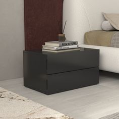 a nightstand with books on top of it next to a bed in a room that has carpeted floors