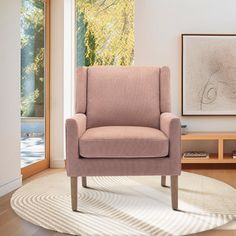 a pink chair sitting on top of a wooden floor next to a white area rug