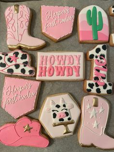 decorated cookies with pink and black frosting are arranged in the shape of cowboy boots