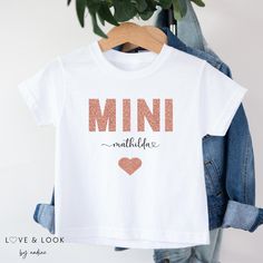 ✨ Personalized T-Shirt for Kids - Matching Outfit ✨ Discover our beautiful personalized t-shirt for children, the perfect piece of clothing for every occasion! Whether for everyday wear, a special occasion or as a charming gift - this t-shirt always ensures a radiant appearance. 🌟 ✨ Glitter prints MINI ✨ The high-quality MINI print in a sparkling glitter look gives this t-shirt a touch of magic. Your child will love wearing this design and feel like a little star. 🌟 🎨 Individual personalization 🎨 The t-shirt can be personalized with your child's name. Simply specify the desired name and we will create a unique piece of clothing that your child will be proud to wear. 🖋️ 👕 High quality materials 👕 Our t-shirt is made of 100% soft cotton and is very comfortable to wear. It is available Cute White T-shirt With Custom Name, White Glitter Print Short Sleeve T-shirt, White Short Sleeve T-shirt With Custom Name, White Names, Mommy Shirts, Matching Outfit, Glitter Print, Mini Short, Short Sleeve Bodysuit