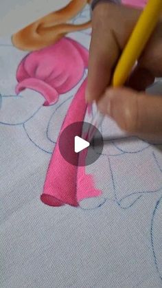 someone is using a pencil to draw on fabric with pink and yellow flowers in the background