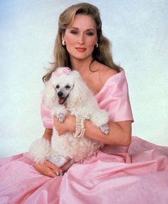 a woman in a pink dress holding a white poodle