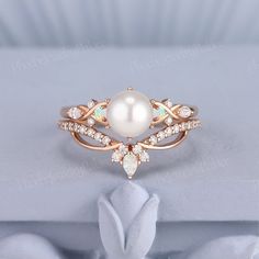 a white pearl and diamond ring sitting on top of a table