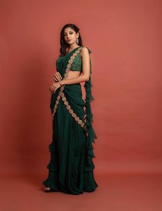 Dark green sequin and thread embroidered georgette blouse with attached soft organza ruffle at shoulder at the back, pre-pleated at center soft organza skirt with frill details and soft organza pre-pleated detachable pallu at waist and shoulder with gold lace embellishment.Dry Clean only. Festive Green Pre-draped Saree With Ruffles, Green Ruffled Blouse For Party, Green Ruffled Sets With Traditional Drape, Festive Ruffled Blouse For Evening, Saree-shape Ruffled Blouse For Party, Evening Organza Lehenga With Ruffles, Green Chiffon Blouse For Party, Evening Organza Sets With Ruffles, Elegant Organza Pre-draped Saree With Ruffles