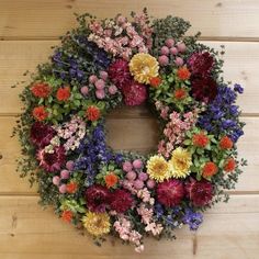 a wreath made out of flowers sitting on top of a wooden floor next to a wall