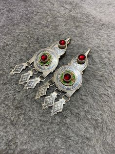 Gorgeous vintage earrings of headdress adornments worn by berber women,made by tiznit jewelers (South of morocco). Decorated with niello,green and yellow enamels and red Glass. To make a niello decoration the jeweler engraves the metal ,spreads the niello a black melted alloy and polishes the surface . Length : 10,7cm Width : 4cm Total weight : 56,2g Antique Jewelry For Pierced Ears, Vintage Ceremonial Earrings With Latkans, Vintage Latkans Earrings For Ceremonial Occasion, Traditional Silver Chandelier Earrings For Ceremonial Occasions, Handmade Vintage Ceremonial Earrings, Traditional Pendant Earrings With Intricate Design, Traditional Filigree Pendant Earrings, Antique Earrings For Ceremonial Festivals, Antique Ceremonial Earrings For Festivals