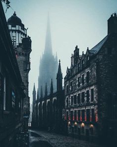 a very tall cathedral towering over a city next to other old buildings in the fog