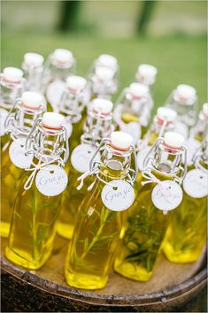 several bottles of olive oil are on a wooden tray with tags attached to the lids