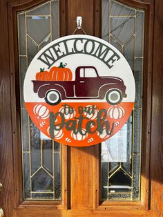 a welcome sign on the front door of a house with pumpkins and an old truck