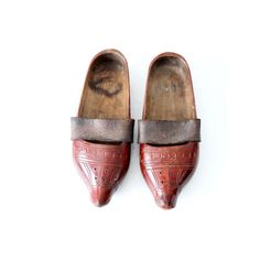 This is a pair of antique wooden clogs. The hand-carved wood sabot feature a red lacquer paint with leather straps across the arch. Traditional Closed Toe Clogs With Leather Sole, Traditional Leather Clogs With Rubber Sole, Vintage Clogs With Leather Sole And Closed Toe, Vintage Leather Sole Closed Toe Clogs, Vintage Leather Sole Slip-on Clogs, Vintage Closed Toe Clogs With Leather Sole, Traditional Leather Clogs With Closed Toe, Traditional Leather Closed-toe Clogs, Traditional Leather Closed Toe Clogs