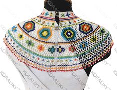 a white crocheted shawl with multicolored flowers and circles on it