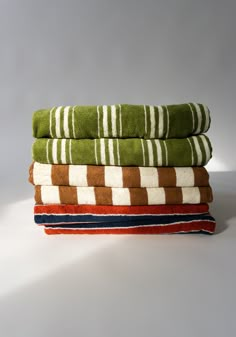 four towels stacked on top of each other in different colors and patterns, all folded neatly