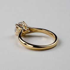 a yellow gold ring with a single diamond on the top and side stones in the middle