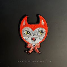 an embroidered patch with a cat's face and yellow eyes, on a black surface