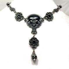 "Black cabochon stone with leaves and skulls with Black crystal eyes Flowers with Black crystal centers & Vitrail crystal details around Adjustable length 14-18\" Lead free pewter Always ethically sourced bones. Nothing has ever been harmed for the purpose of our jewelry. All pieces are made-to-order despite the \"in stock\" number in the listing. Time frame varies from piece to piece so please message us if you need something by a certain date and we will do our best. A portion of our profi Nickel-free Gunmetal Gothic Jewelry, Nickel Free Black Skull Necklace, Black Nickel Free Skull Necklace, Gothic Oval Metal Jewelry, Black Nickel-free Skull Necklace, Vintage Black Skull Jewelry, Gothic Silver Oval Necklace, Black Skull Necklace With Oxidized Finish, Black Oxidized Skull Necklace