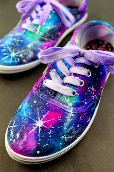 two colorful shoes with purple laces and stars painted on the upper part of them