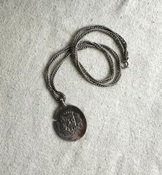 You will receive this fun faux coin pensant on a 24" chain.  It measures 1 7/8" x 1 1/4" and has a 4 mm bail opening.  The necklace is cast in a silver tone base metal and it is unbranded.  It is in good preowned wearable condition with minimal signs of wear. We have rebranded, and since December 2023 we are Lazy Frog Thrifters.  We have been flipping high end home decor that we find at thrift stores, yard sales, flea markets, and estate sales.  Come check out the old and tired items that we have given a French Country look or Cottage Core vibe to at:  https://lazyfrogthrifters.etsy.com Vintage Silver Dog Tag Necklace, Vintage Medallion Silver Chain Jewelry, Nickel Free Silver Medallion Necklace, Silver Coin-shaped Medallion Necklace, Silver Medallion Locket Necklace, Vintage Silver Medallion Metal Necklace, Vintage Silver Medallion Necklace, Collectible Silver Metal Locket Necklace, Silver Round Medallion Necklace Collectible