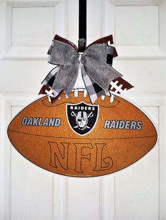 a football shaped door hanger with the oakland raiders logo on it and a bow