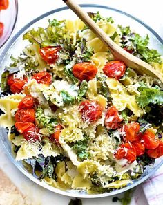 a bowl filled with pasta, tomatoes and broccoli