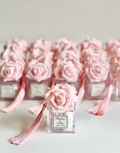 pink roses are in small glass bottles with tassels on the top and bottom