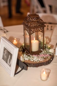 a small lantern is on top of a table with flowers and candles in front of it